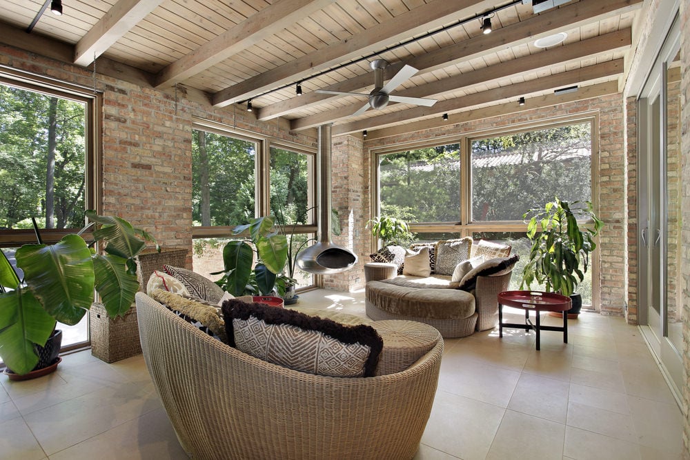 A tropical type of sunroom incorporated with some detailed chairs, bricked walls, tiled floor and of course, some potted tropical plants.